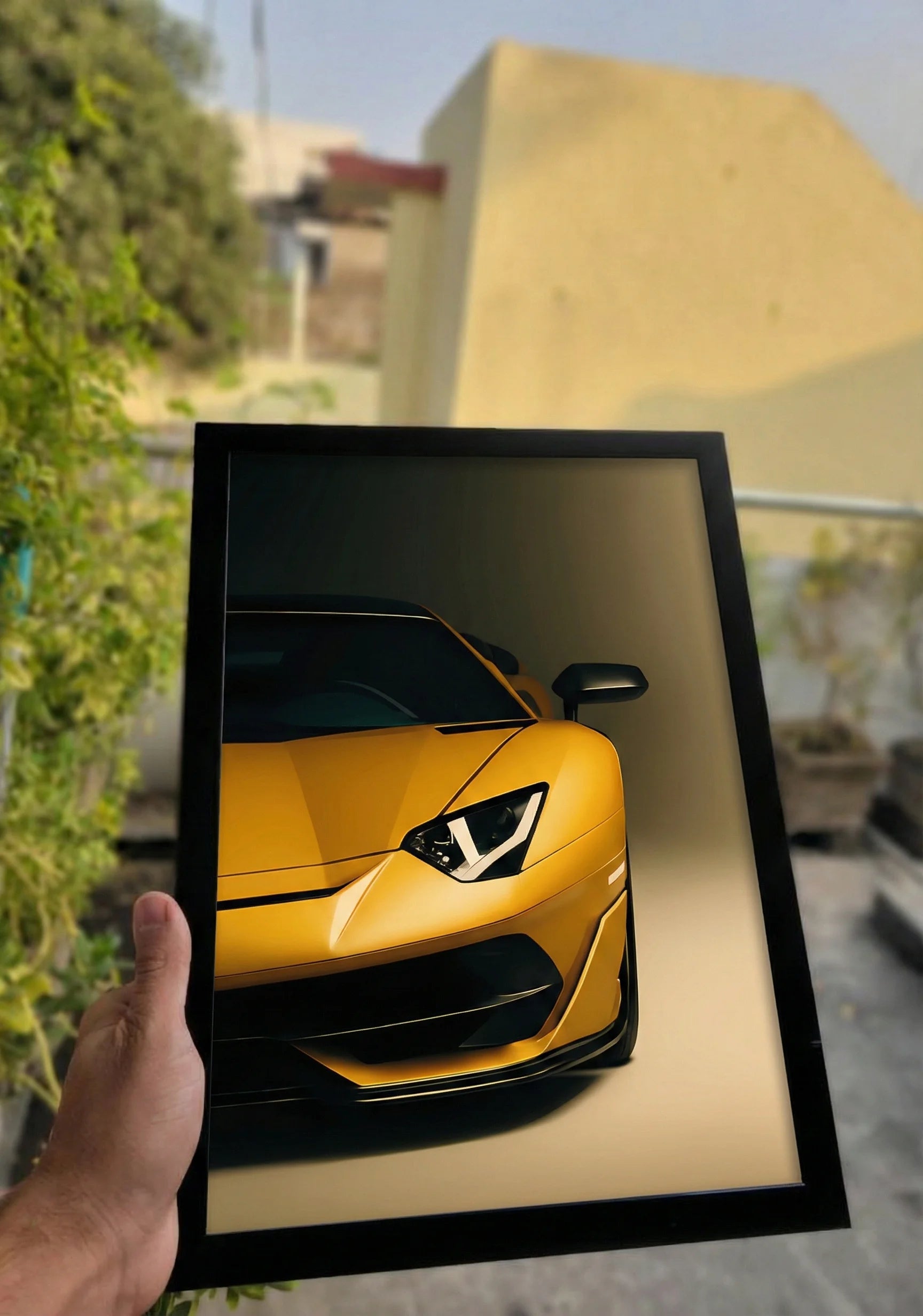 Golden sports car in a black frame held by a hand outdoor for boys room decor