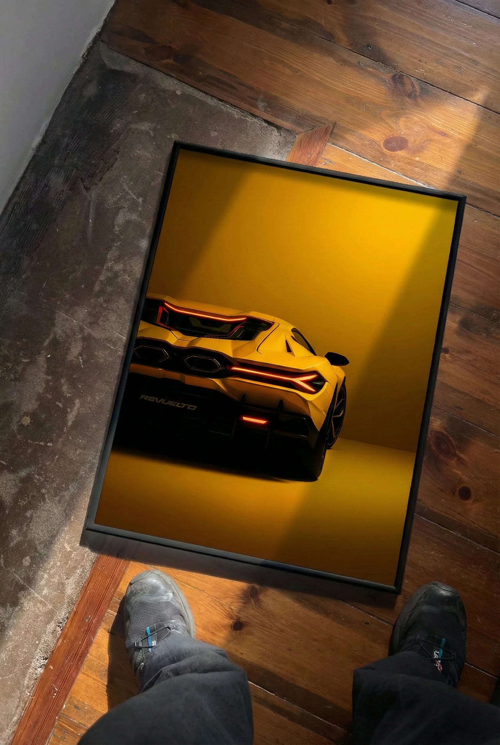 Yellow sports car on a yellow background in a black frame on a wooden floor.